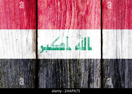 Motif de grunge du drapeau national de l'Irak isolé sur des panneaux de clôture en bois altérés. Banque D'Images