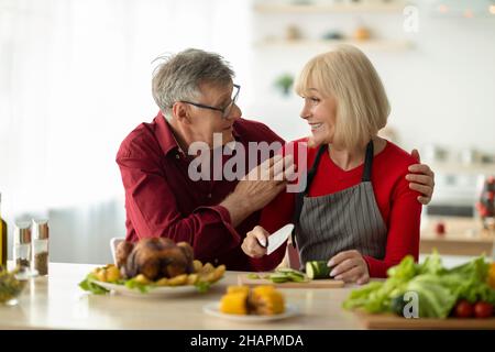 Couple de personnes âgées aimant se regardant les unes les autres tout en préparant la dinde rôtie traditionnelle pour le dîner de Noël à la maison Banque D'Images