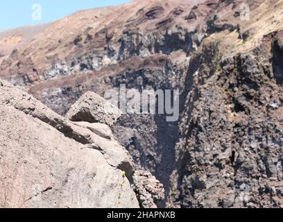 Détail de la lave et en arrière-plan le grand cratère du volcan latent Vésuve près de la ville de Naples dans le sud de l'Italie Banque D'Images