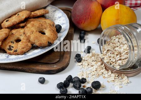 Quelques biscuits faits maison de flocons d'avoine avec des raisins secs et du miel, quelques flocons d'avoine, des arandados et des fruits sur une table.Concept d'alimentation naturelle et saine. Banque D'Images