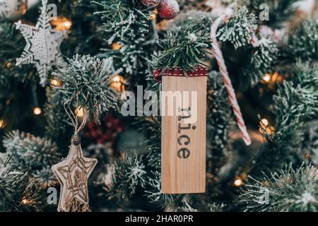 Photo en gros plan d'un ornement de noël en bois avec texte beau suspendu sur un arbre de noël. Banque D'Images