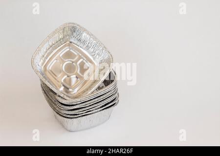 Bols en aluminium non utilisés, propres, à usage unique, conteneurs en aluminium - emballage à emporter - empilés sur fond blanc avec espace de copie Banque D'Images