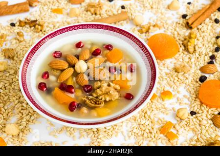 Dessert turc traditionnel Ashure ou Noah's Pudding dans un bol blanc sur des ingrédients d'ashura non cuits Banque D'Images