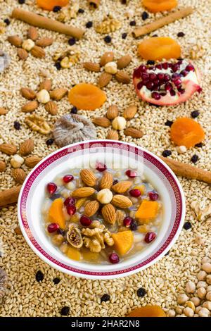 Dessert turc traditionnel Ashure ou Noah's Pudding dans un bol blanc sur des ingrédients d'ashura non cuits Banque D'Images