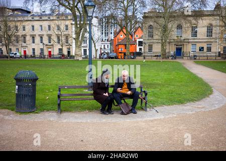 Un vieux couple s'est assis sur un banc de parc à l'aide d'un smartphone Banque D'Images