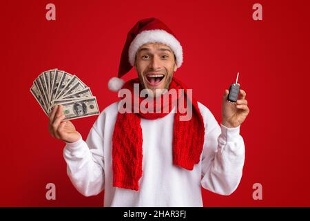 Bonus Noël.Un homme excité dans le chapeau de père Noël tenant la clé de voiture et l'argent Banque D'Images