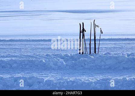 Silhouette de deux paires de skis et de bâtons pour le ski de fond.Ils sont plantés verticalement dans la neige à côté d'un sentier pour le ski de fond. Banque D'Images