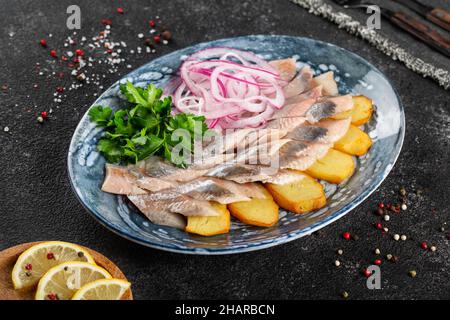 Hareng salé avec pommes de terre cuites au four et oignons. Banque D'Images