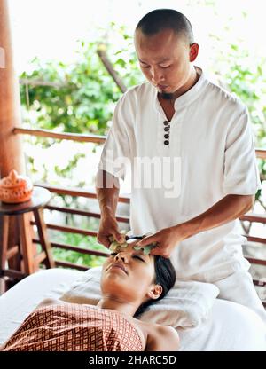 Femme recevant le visage de Guasha à Kamalaya, Koh Samui, Thaïlande.Une femme reçoit un visage de Guasha, une pratique médicale traditionnelle chinoise utilisant le jade. Banque D'Images