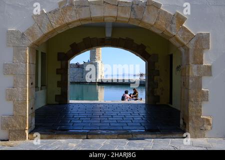 Vue sur le couple et le phare à travers un portail dans la digue à Rethymno, Crète, Grèce Banque D'Images