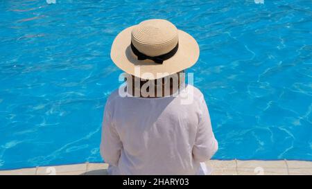 Femme âgée se détendant près de la piscine extérieure bleue de l'hôtel.Les gens apprécient leurs vacances d'été.Tout compris, vue sur l'arrière Banque D'Images