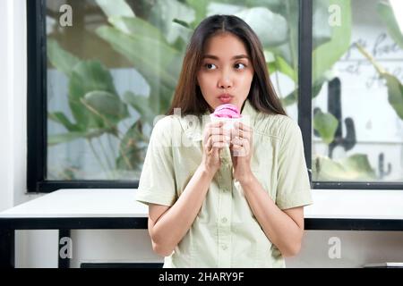 Femme asiatique tenant une tasse de glace à la fraise dans le café Banque D'Images