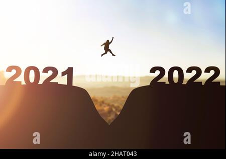 Silhouette de l'homme gras sautant de la colline 2021 à la colline 2022.Bonne année 2022 Banque D'Images