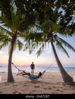 NaJomtien Pattaya Thaïlande, Hammock sur la plage au coucher du soleil avec des palmiers. Couple homme et femme à mi-âge regardant le coucher du soleil à Na Jomtien Pattaya.Femme asiatique et homme européen Banque D'Images