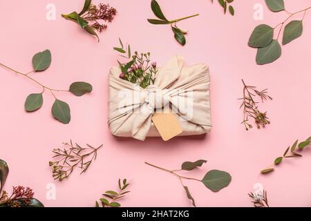 Composition avec boîte cadeau enveloppée de coton et décor floral sur fond rose Banque D'Images