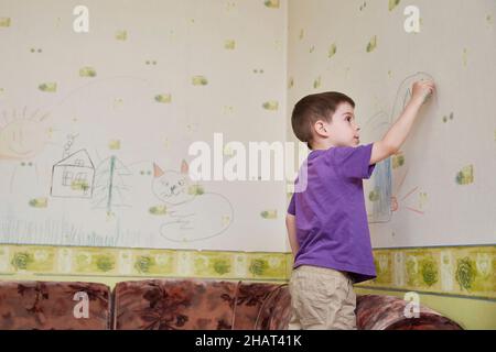 le preschooler puise sur le papier peint dans une pièce pendant le verrouillage et l'isolement pendant la pandémie du coronavirus covid-19 Banque D'Images