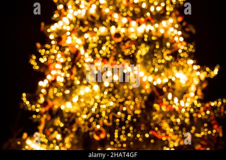 Arrière-plan défoqué de l'arbre de Noël avec guirlandes.Luminosité bokeh.Ambiance de la veille de noël. Banque D'Images