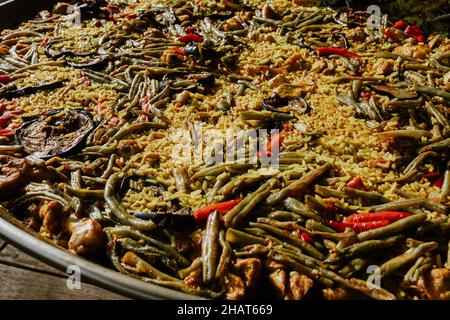 Processus de préparation de la paella dans une casserole avec du poulet et des légumes et l'assaisonnement à la main du chef et la cuisine sur une terrasse en Espagne Banque D'Images