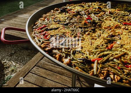 Processus de préparation de la paella dans une casserole avec du poulet et des légumes et l'assaisonnement à la main du chef et la cuisine sur une terrasse en Espagne Banque D'Images