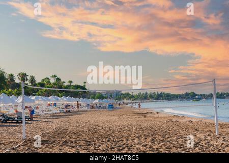 Vue sur la plage, chaises longues, parasols, drapeaux et petite côte ondulée du côté d'Antalya. Mise au point sélective. Banque D'Images