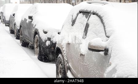 Rangée de voitures couvertes de neige pendant les fortes chutes de neige, tempête de neige dans la ville Banque D'Images