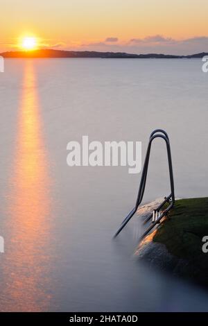 Échelle descendant vers la mer au coucher du soleil Banque D'Images