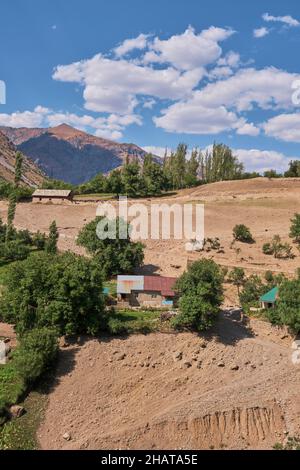 Une ferme humble sur une colline escarpée pendant l'été sec.Dans la région du réservoir du lac Charvak près de Tachkent, Ouzbékistan. Banque D'Images