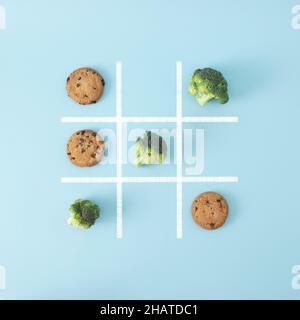 Dans ce jeu de société, le brocoli bat les biscuits aux pépites de chocolat, ce qui signifie que la nourriture saine est meilleure que la nourriture de pourriels, alors gagnez ce jeu.Fond de lit plat créatif Banque D'Images