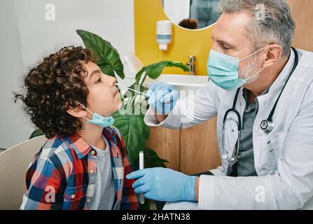 Garçon mauri pendant le test PCR de COVID-19 dans un laboratoire médical.Médecin prenant un écouvillon nasal pour un échantillon de coronavirus Banque D'Images