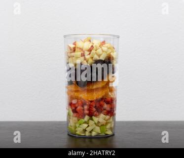 Une grande variété de fruits coupés sont placés sous forme de couches dans un pot en verre.Concept de préparation des desserts. Banque D'Images