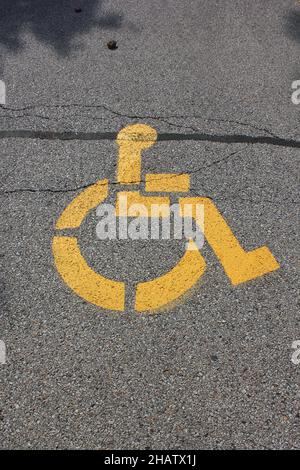 Panneau jaune vif pour handicapés peint sur la chaussée en asphalte. Banque D'Images