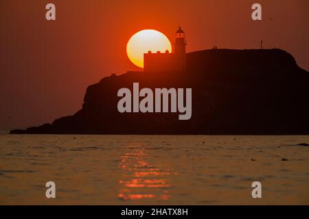 Le soleil se lève derrière un phare sur l'île de Fidra, au large de la plage de Yellowcraig à East Lothian.Les Lothians est de profiter d'un temps plus chaud aujourd'hui avec un pic à 19 degrés.Crédit: Euan Cherry Banque D'Images