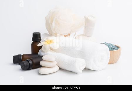 Massage spa, fleurs exotiques de plumeria tropicale, sérum, gommage aux herbes, pierres zen, serviettes blanches et cristal de sel bleu sur fond blanc Banque D'Images