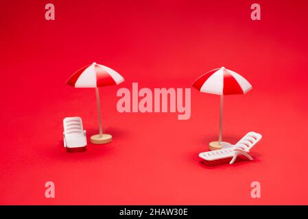 Deux chaises longues et parasols rouges sur fond rouge.Copier l'espace. Banque D'Images