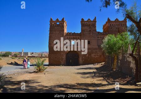 Ancienne porte de la ville avec une femme et un enfant marocains dans la rue, Agdz, Maroc Banque D'Images