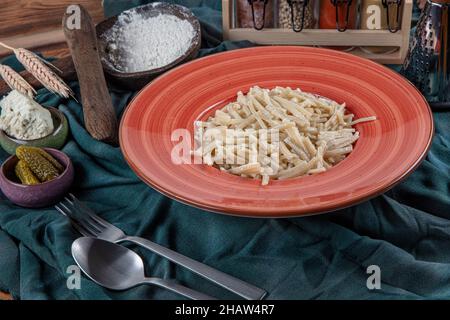 Nouilles turques faites à la main au fromage (nom turc : eriste) dans une assiette en porcelaine.Erishte de la cuisine turque traditionnelle. Banque D'Images