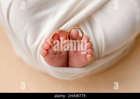 Les petits pieds d'un nouveau-né avec les anneaux de mariage de ses parents sur ses doigts.Traditions familiales Banque D'Images