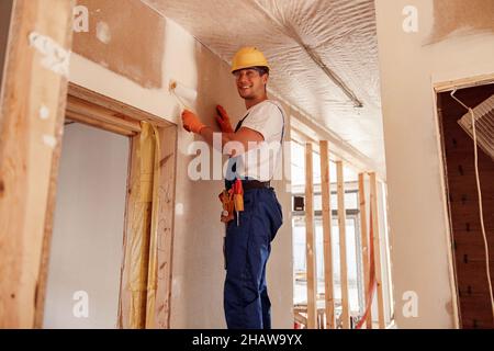 Homme gai peint mur dans la maison en construction Banque D'Images