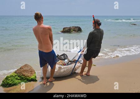 Deux jeunes hommes sur la plage tirant un sac lourd de déchets plastiques, nettoyage de plage, Almeria, Andalousie, Espagne Banque D'Images