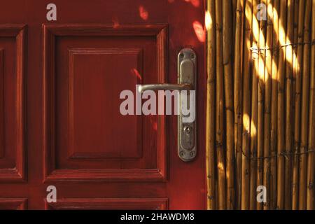 Gros plan sur une poignée de porte rouge et un mur en osier Banque D'Images