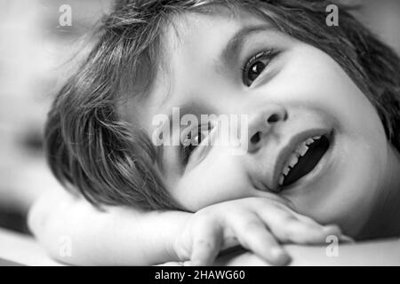 Petit garçon souriant, allongé sur le bureau dans la salle de séjour. Banque D'Images