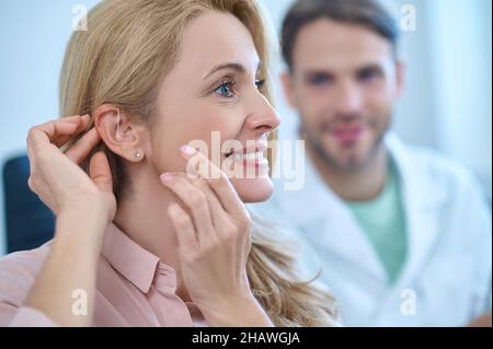 Profil de la femme avec ses mains touchant l'oreille Banque D'Images