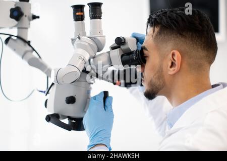 Technologies modernes pour la santé.Arab Doctor utilisant le microscope dentaire en clinique Banque D'Images