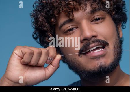 Calme mignon homme en utilisant sa soie dentaire Banque D'Images
