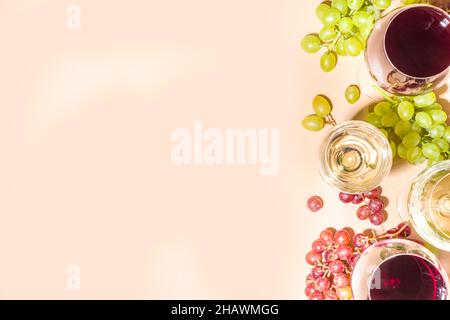 Verres de vin rouge et blanc avec soleil et ombres, avec bouteille et carafe, bouquet de raisins, sur fond crémeux, vue sur le dessus plat vin Banque D'Images