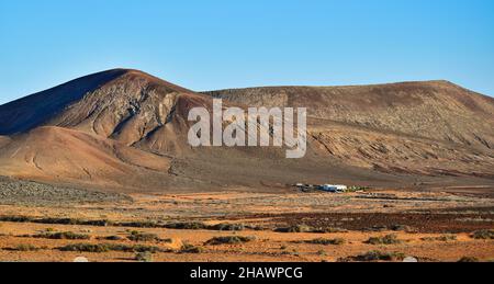 Magnifique paysage volcanique avec une maison blanche en face.Près de Costa Teguise, Lanzarote, Iles Canaries, Espagne.Image prise sur le terrain public. Banque D'Images