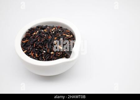Riz gluant noir dans un bol blanc NON découpé sur fond blanc. Banque D'Images