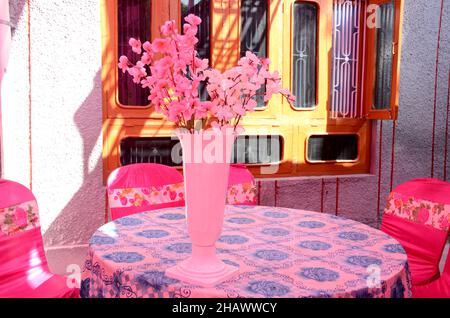 gros plan la fleur blanche rose artificielle dans le pot blanc sur un fond brun rose hors foyer. Banque D'Images