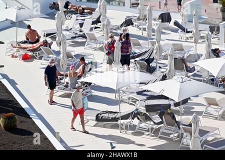 Les vacanciers portant des masques protecteurs contre Covid-19 sont vus par des chaises longues dans un hôtel de Tenerife, en Espagne.Décembre 2021. Banque D'Images