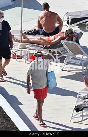 Les vacanciers portant des masques protecteurs contre Covid-19 sont vus par des chaises longues dans un hôtel de Tenerife, en Espagne.Décembre 2021. Banque D'Images